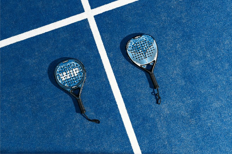 Twee rackets naast elkaar op de witte lijnen van een blauwe baan.